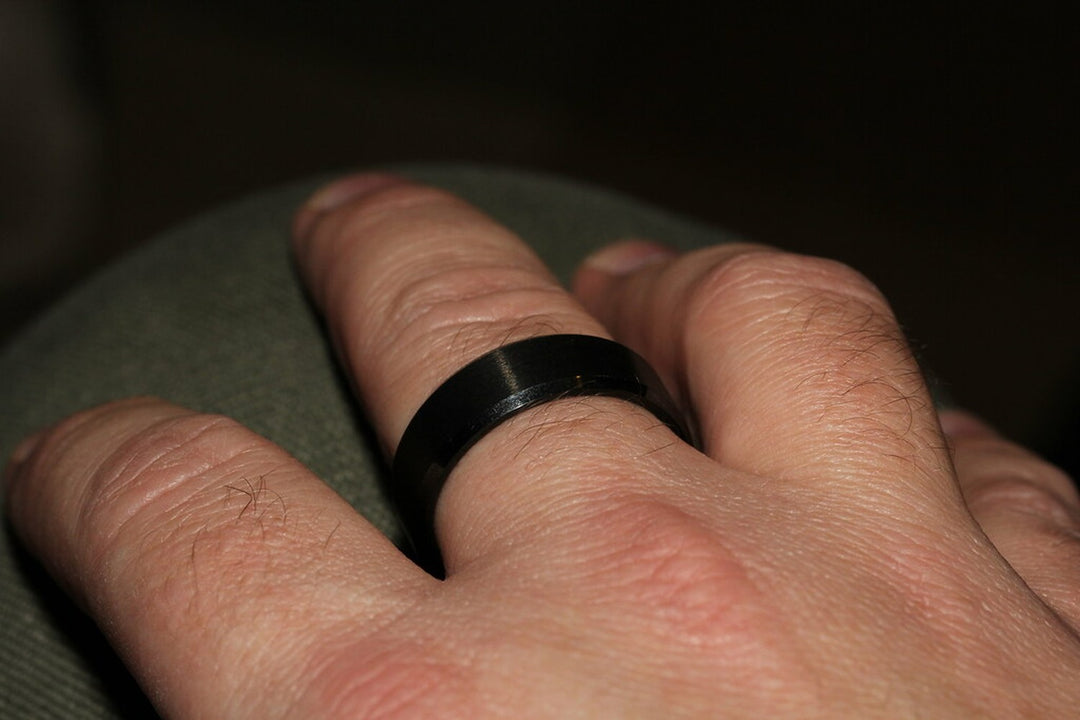 black tungsten carbide wedding band on a man's hand — tungsten carbide vs tungsten