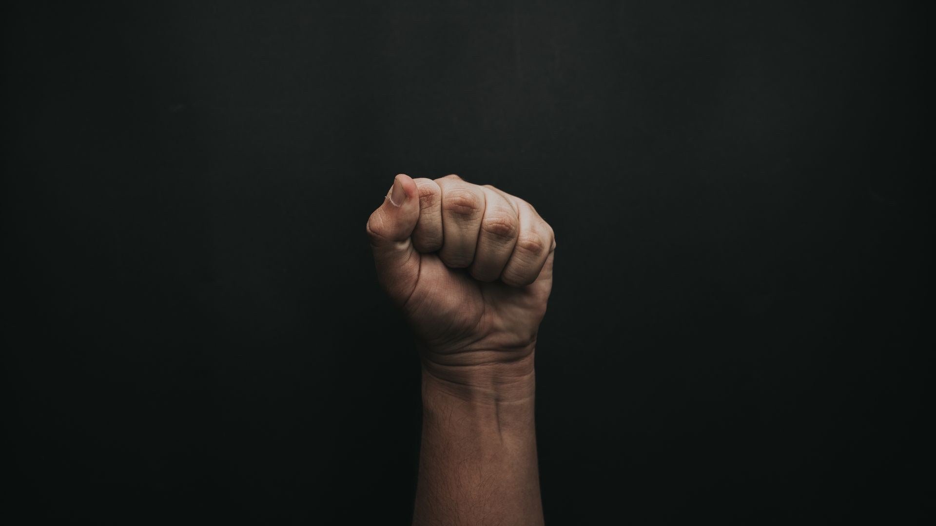 masculine fist on a dark background - mens ring sizing guide