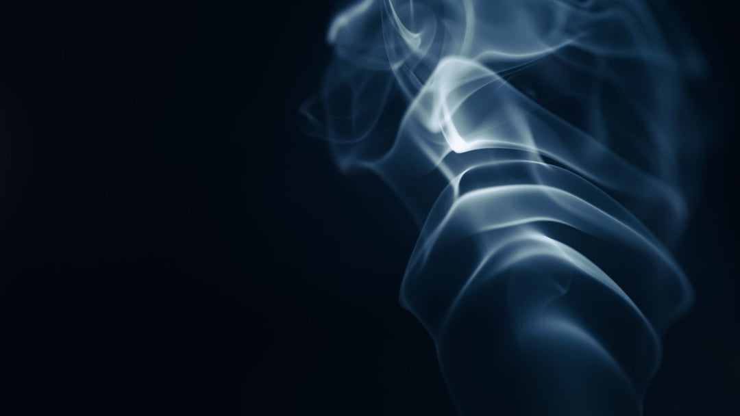 Pale blue-gray smoke curling against a near-black background