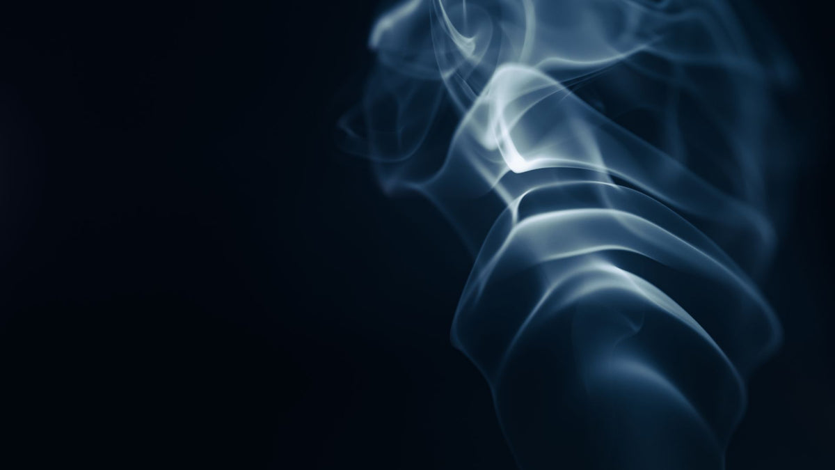 Pale blue-gray smoke curling against a near-black background
