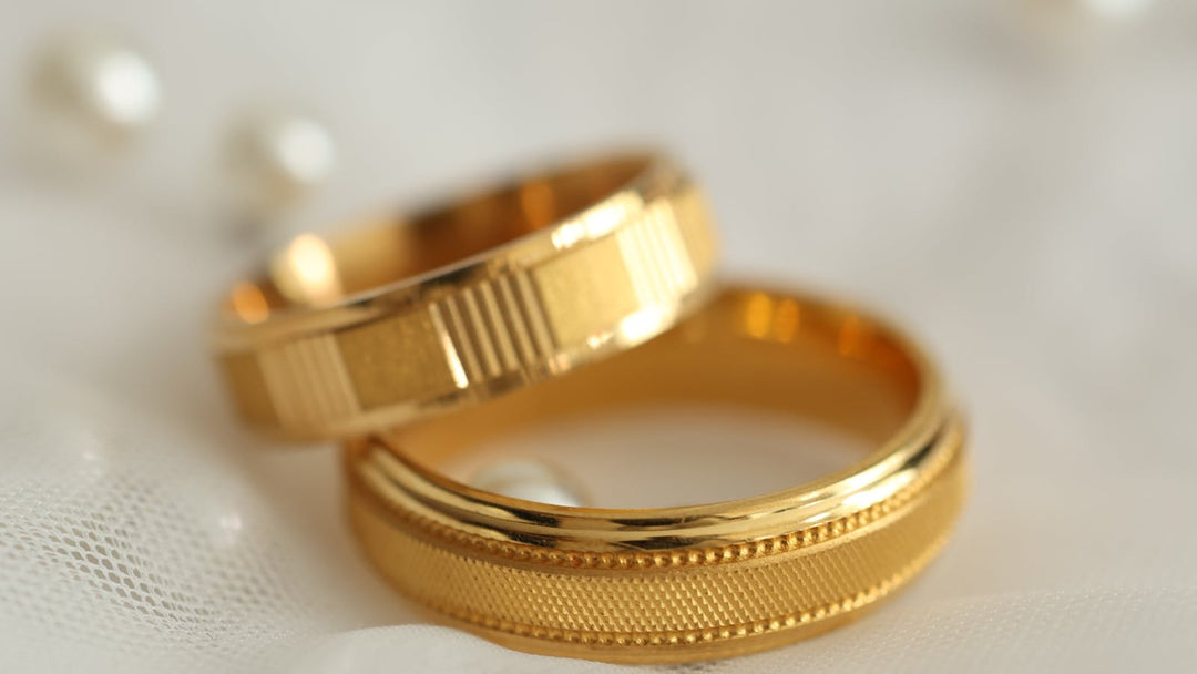 which goes first engagement ring or wedding band — two gold wedding bands on white fabric — FoundryCut