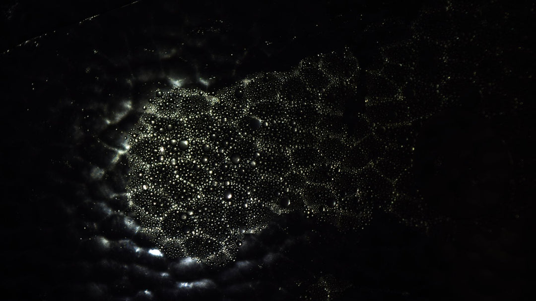 scattered water droplets beaded on a black surface, evoking the rinse-and-dry step in a tungsten ring care routine