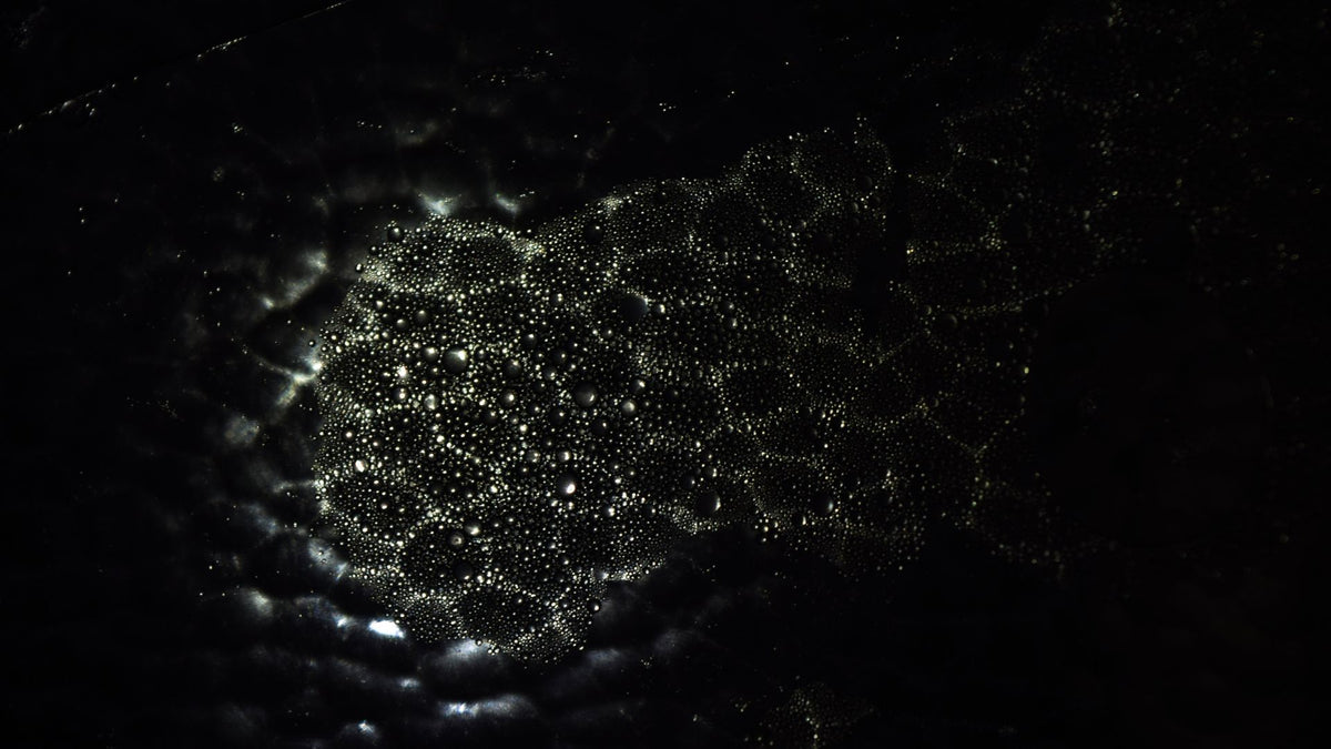 scattered water droplets beaded on a black surface, evoking the rinse-and-dry step in a tungsten ring care routine