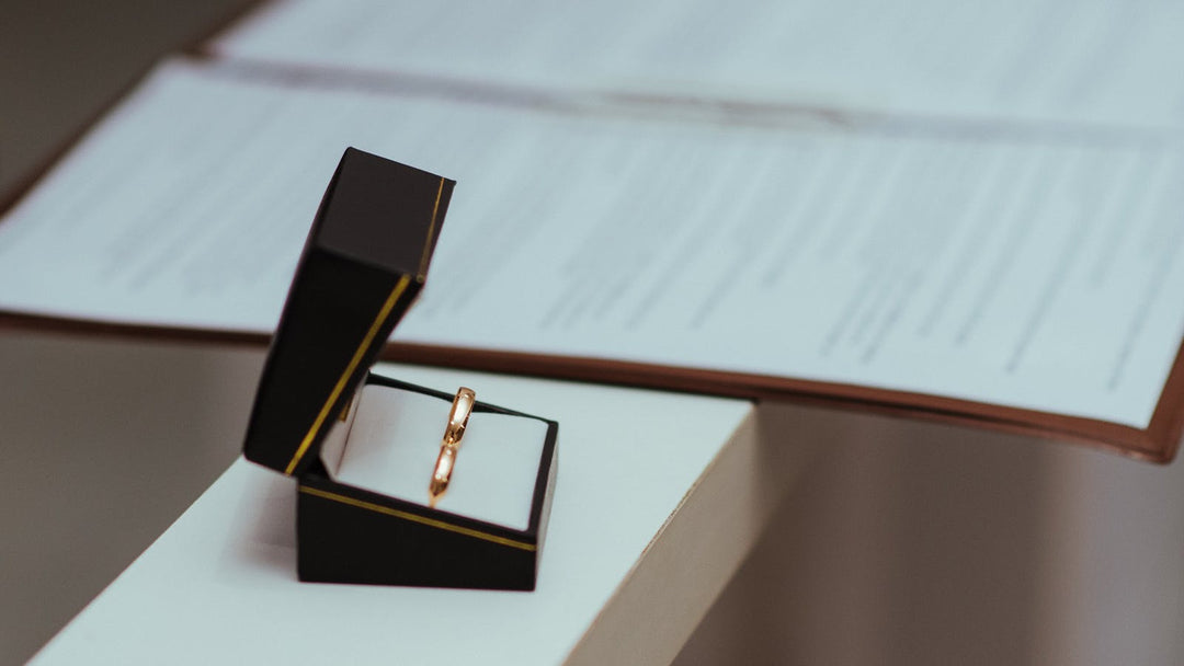 How much should a wedding ring cost — plain rose-gold band in a black ring box on a contract — FoundryCut