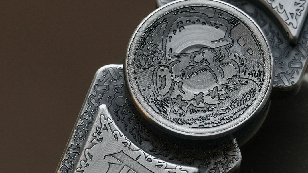Close-up of engraved steel pieces with deep-cut ornamental patterns on a brushed metal surface against a dark brown background