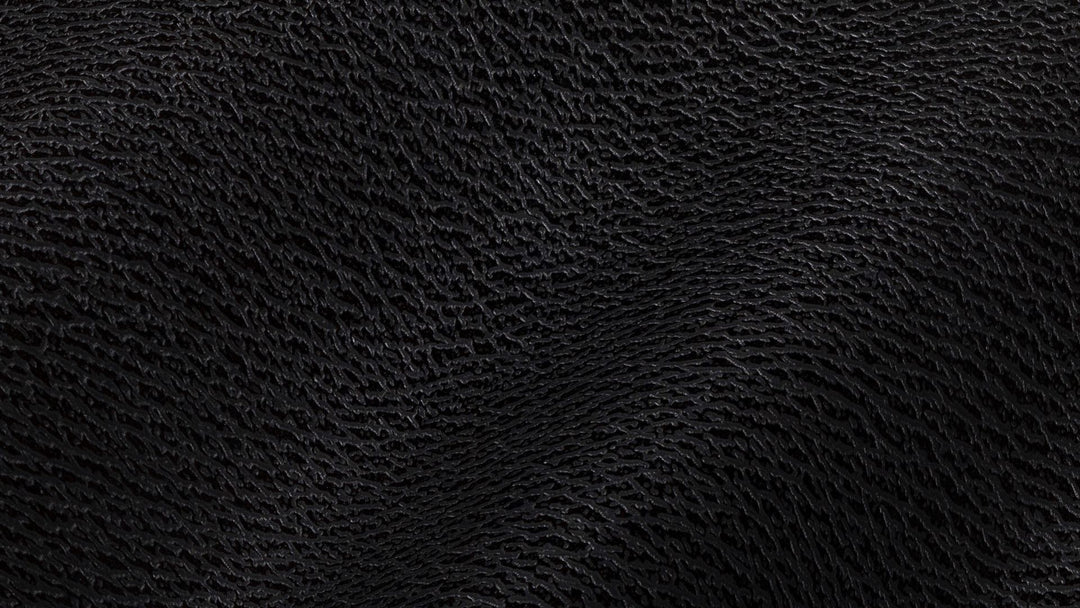 Close-up of dark pebbled black leather falling in soft folds, lit low from one side