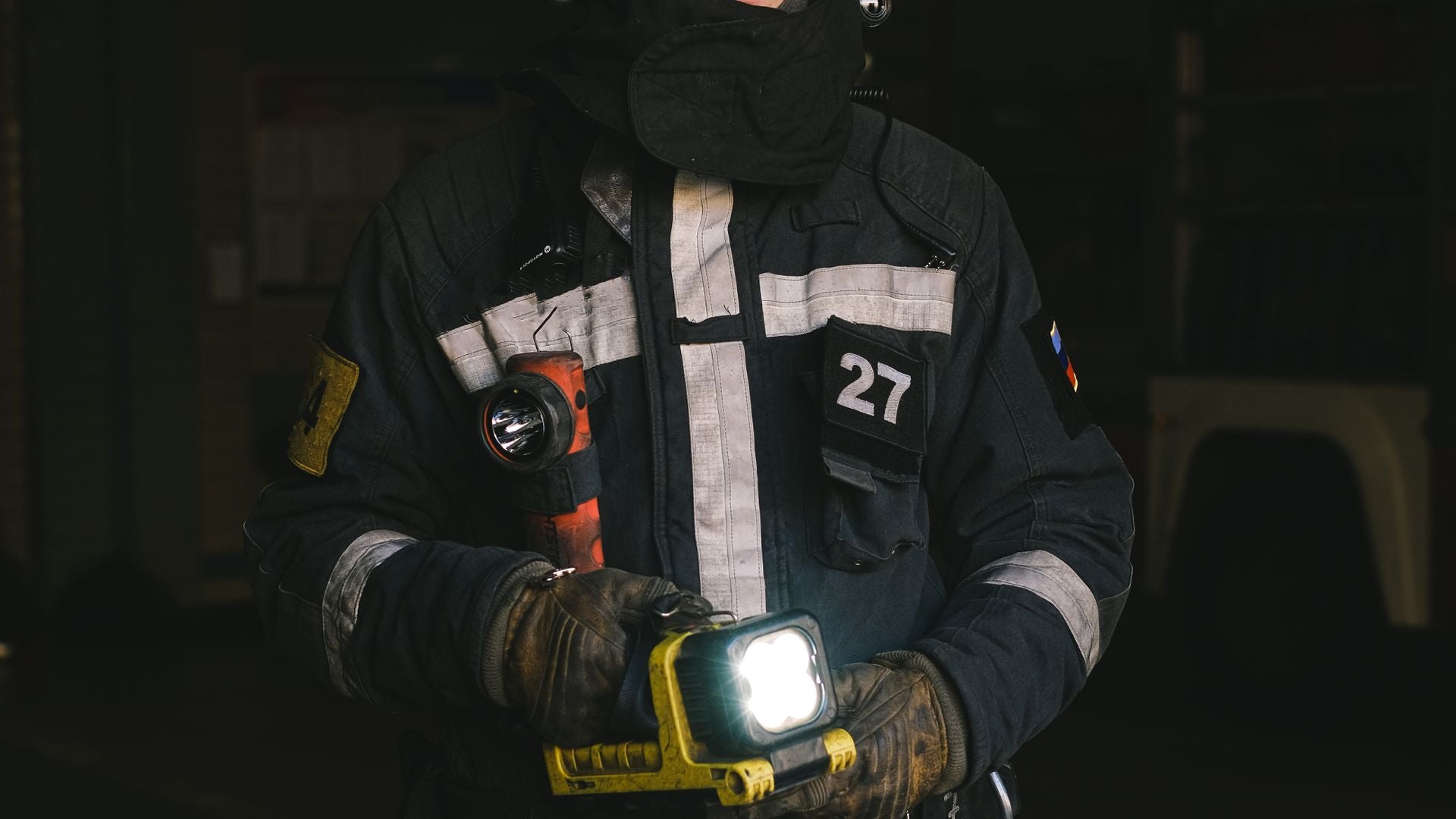wedding bands for firefighters - firefighter in dark turnout gear holding a work light