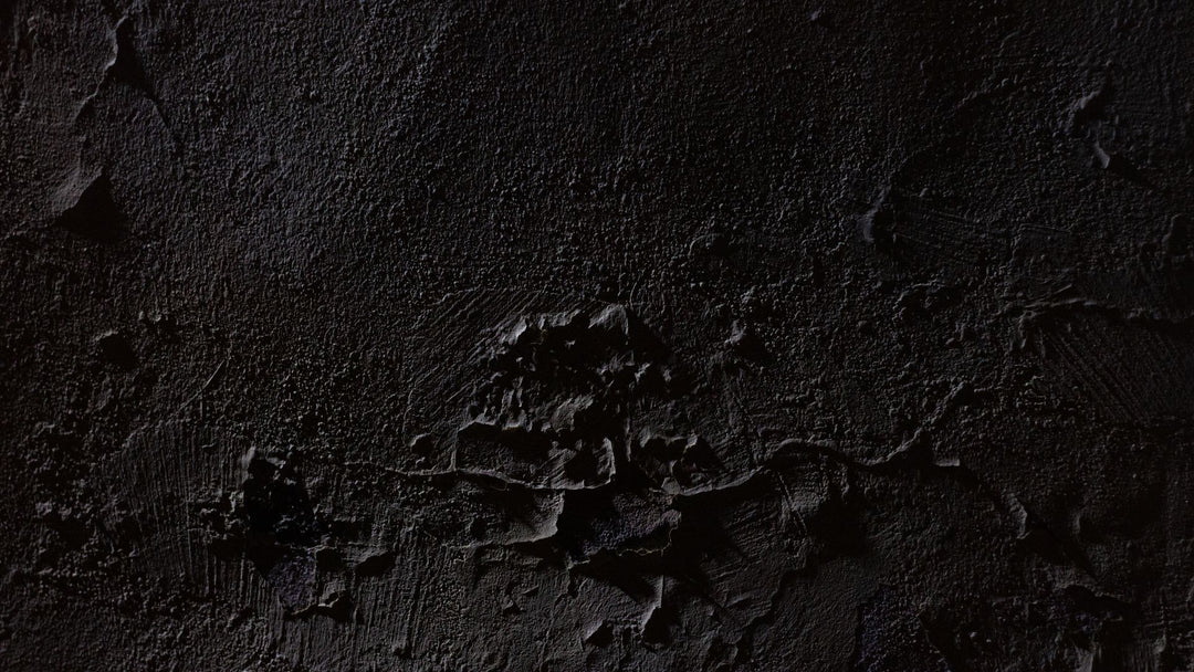 Dark textured plaster wall lit from the upper left, with chipped patches and trowel marks breaking the surface around the center