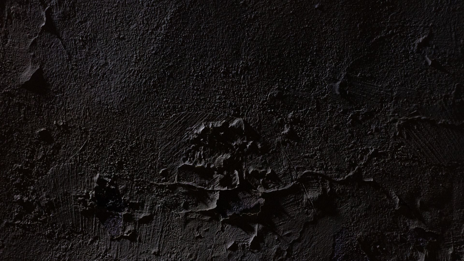 Dark textured plaster wall lit from the upper left, with chipped patches and trowel marks breaking the surface around the center