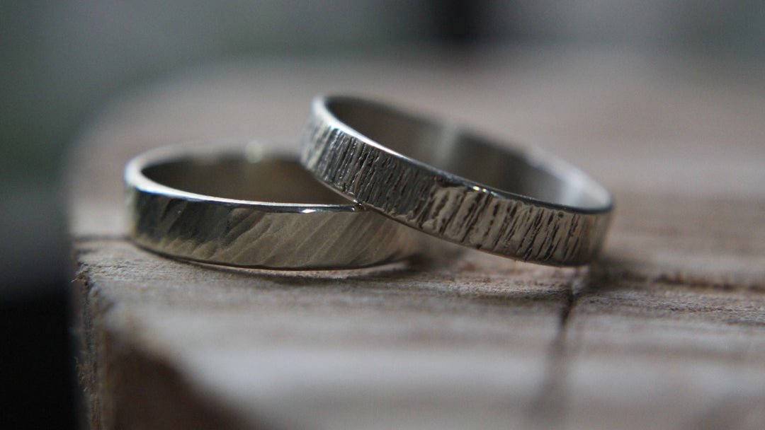 hammered tungsten rings — two textured silver wedding bands on rustic wood — FoundryCut
