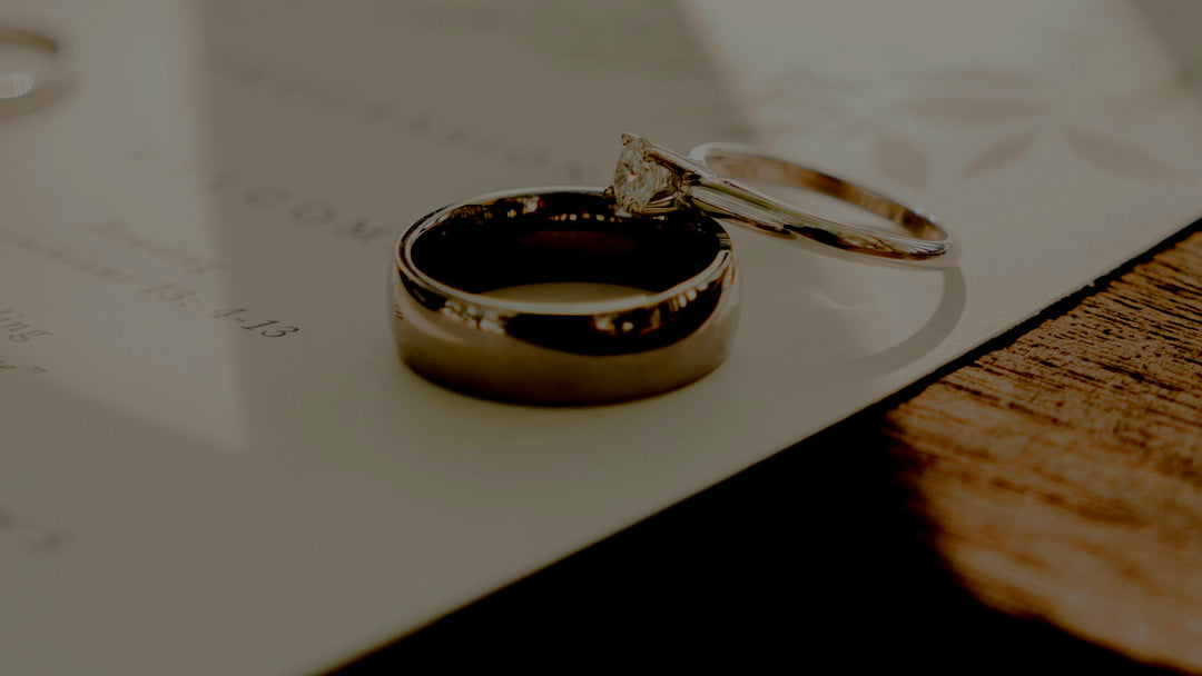 wedding ring vs wedding band — a plain men's wedding band beside a stone-set engagement ring