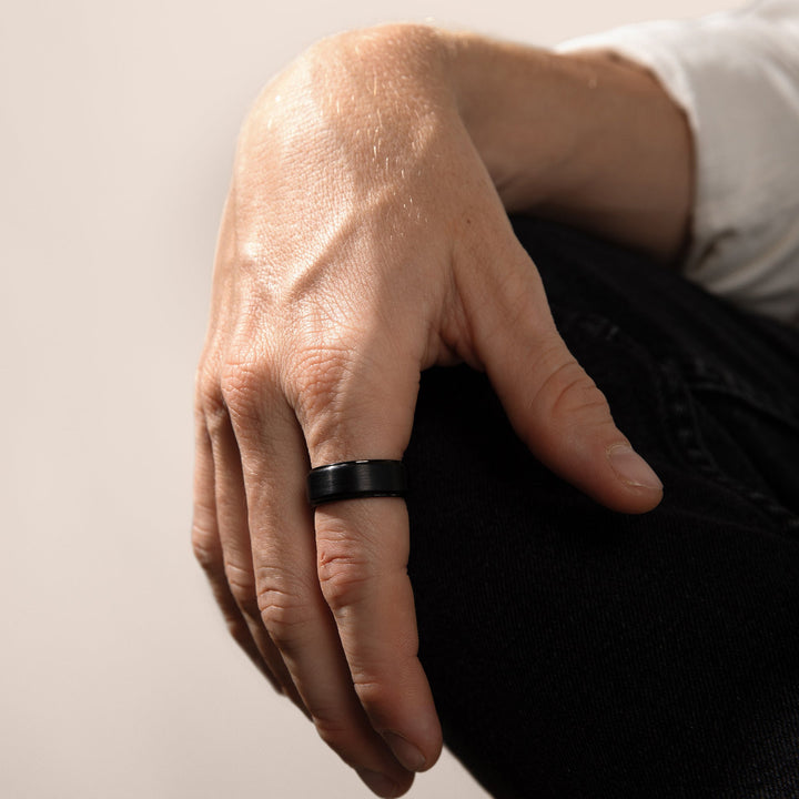 Monolith tungsten wedding band on hand — close-up lifestyle